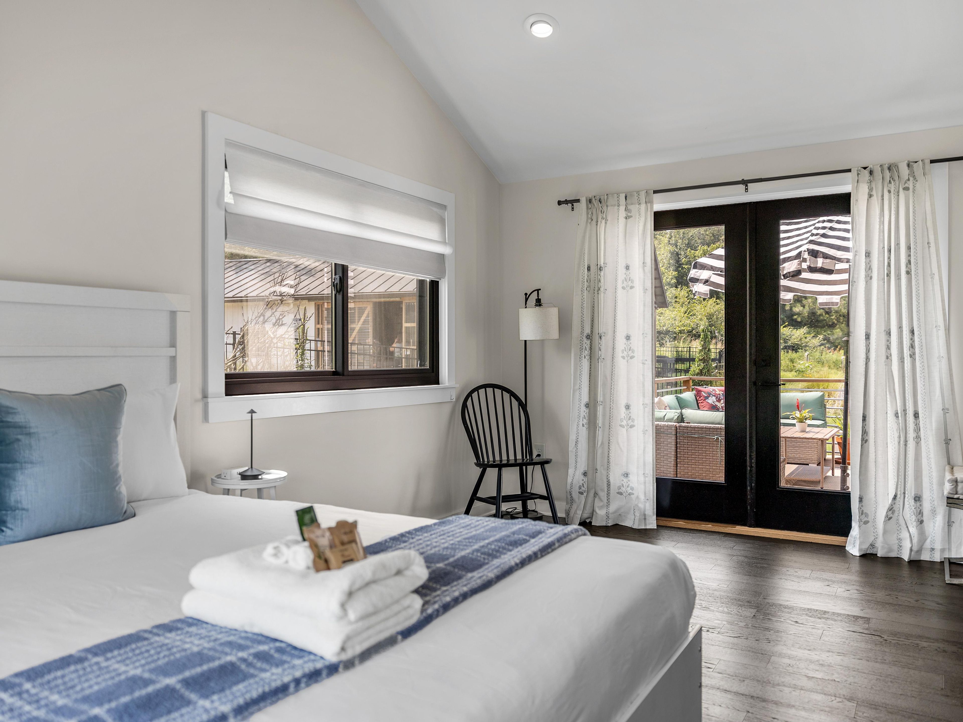 Ein Hotelzimmer mit Bett, einem Sessel, einem Tisch und Blick ins Freie.