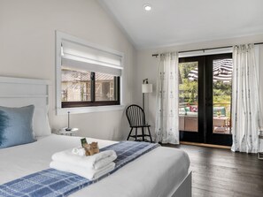 Ein Hotelzimmer mit Bett, einem Sessel, einem Tisch und Blick ins Freie.