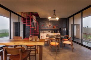 Una cocina moderna con una escalera espiral roja, un comedor con mobiliario de madera y ventanas amplias que ofrecen vistas al exterior.