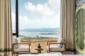 Una habitación con dos sillas orientadas a un gran ventanal con vistas a un lago y montañas.