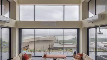 A spacious living area with a high ceiling, large windows, and a view of a distant landscape.
