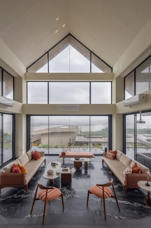 Un amplio espacio habitable con techo alto, ventanas grandes y vista a un paisaje lejano.