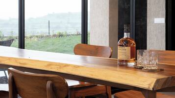 A dining table with chairs, a bottle of whiskey, and glasses.