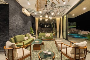 Un intérieur moderne avec un canapé vert, des chaises en bois, une table basse et un sol à motifs.