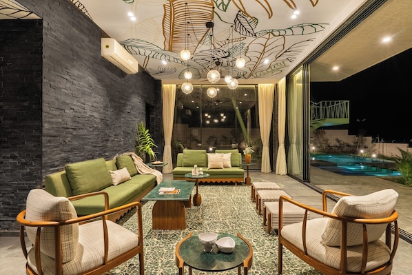 A modern interior with a green sofa set, wooden chairs, a coffee table, and a patterned floor.
