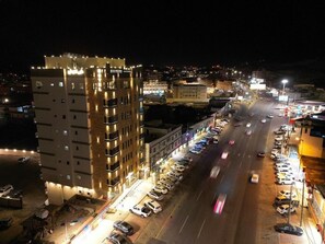 A multi-story building with a parking lot in front, surrounded by other buildings and a busy road with moving vehicles.