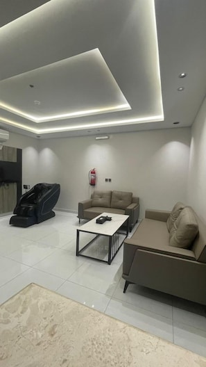 Una sala de estar moderna con un sofá, un sillón de masaje, una mesa de centro e iluminación empotrada en el techo.