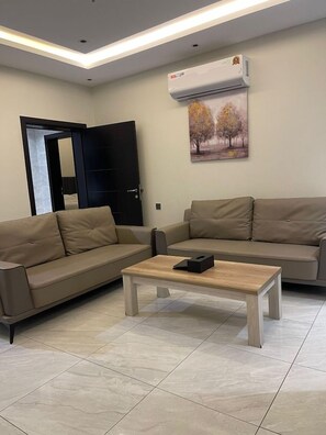 Uma sala de estar com dois sofás, uma mesa de centro e um aparelho de ar condicionado.