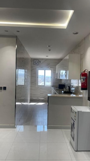 Cozinha moderna com ilha central, extintor de incêndio e vista da cidade por grandes janelas.