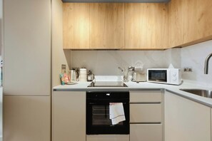 Ett modernt kök med träskåp, diskmaskin, mikrovågsugn och diskho.
