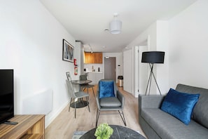 Una sala moderna con sofá, mesa de centro, televisor y comedor con sillas y mesa.