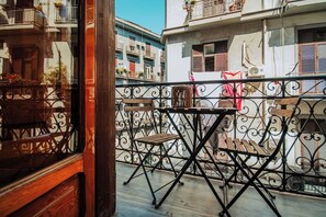 A balcony with a wrought iron railing, a wooden table, and a folding chair. - Lara's Home (Naples)