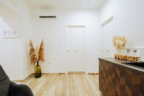A modern hotel room with a wooden floor, a reception desk, and a door. - Lara's Home (Naples)