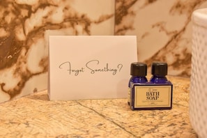A bathroom setting with a marble countertop, a bottle of bath soap, and a card with the text 'Forget Something?'