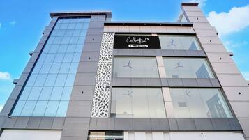 A modern building with a glass facade, a sign indicating a collection service, and a decorative metal panel.