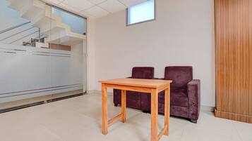 A room with a wooden table, two dark chairs, a glass partition, and a small window.