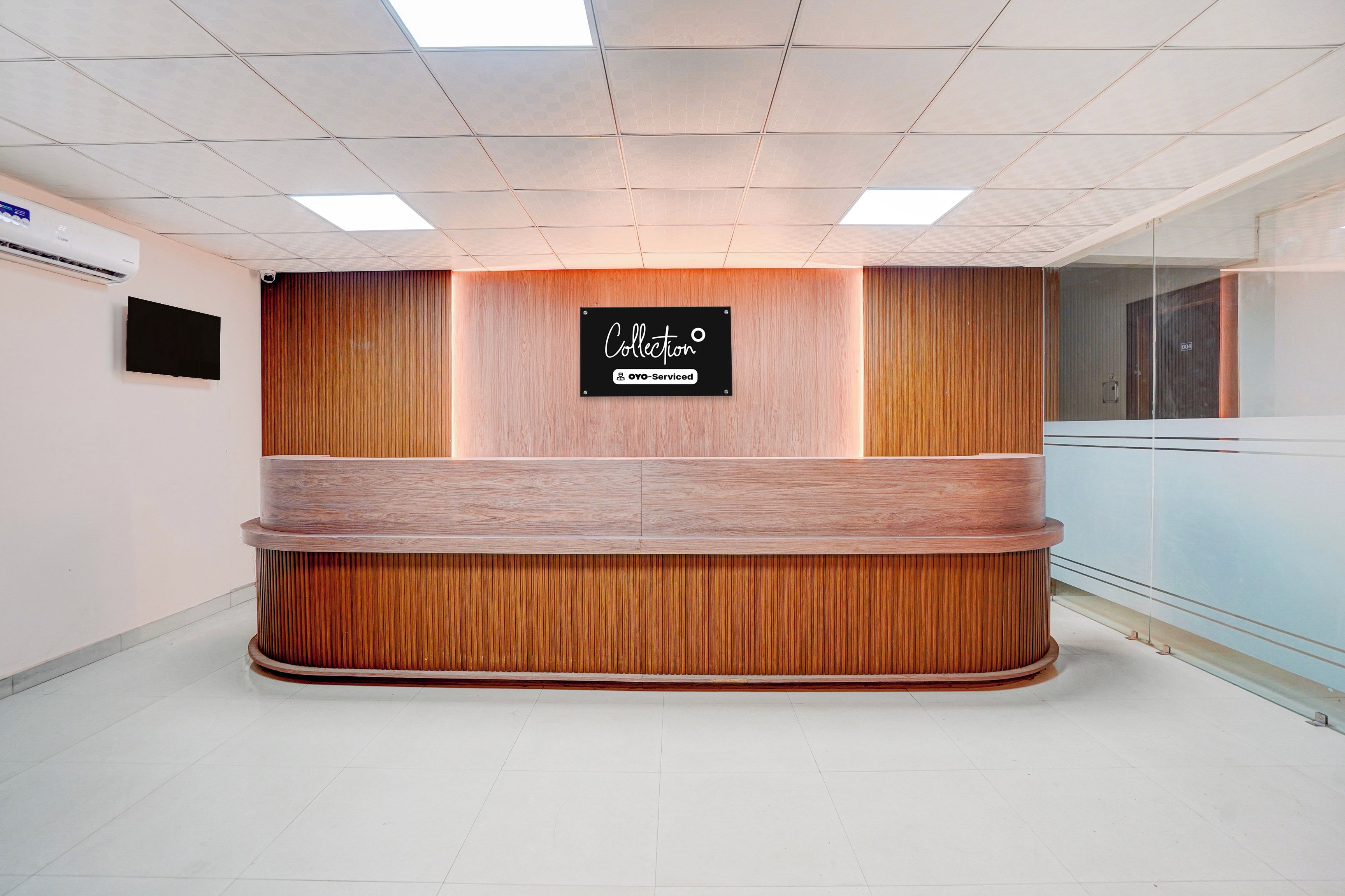 A reception desk with a wooden finish, a sign above it, and a tiled floor.