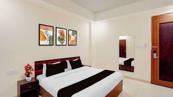 A hotel room with a bed, bedside tables, a nightstand, a mirror, and artwork on the wall.