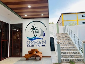 The exterior of the Ocean Star Hotel with a wooden ceiling, a palm tree logo, and a staircase with patterned tiles. - Ocean Star Hotel Coron (Coron)