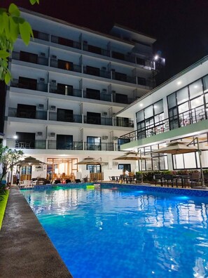 A multi-story hotel with a swimming pool, outdoor seating, and a well-lit entrance. - Ocean Star Hotel Coron (Coron)