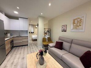 A compact living space with a kitchenette, a sofa, a coffee table, and a bed. - Aires de Salamanca Melibea (Salamanca)