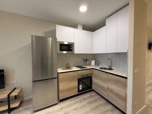 A compact kitchen with a built-in refrigerator, microwave, and oven, featuring a minimalist design with light wood cabinetry and a marble backsplash. - Aires de Salamanca Melibea (Salamanca)