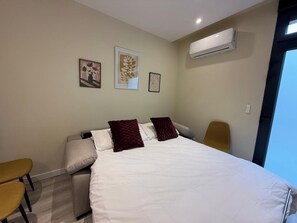 Ein Hotelzimmer mit einem Bett, zwei Stühlen, einer Klimaanlage und Wandbildern.