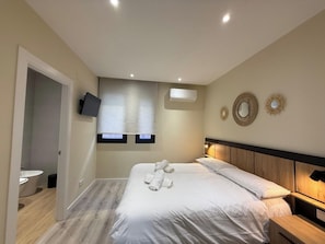 A hotel room with a bed, bedside table, wall-mounted TV, air conditioning unit, and decorative wall mirrors. - Aires de Salamanca Melibea (Salamanca)