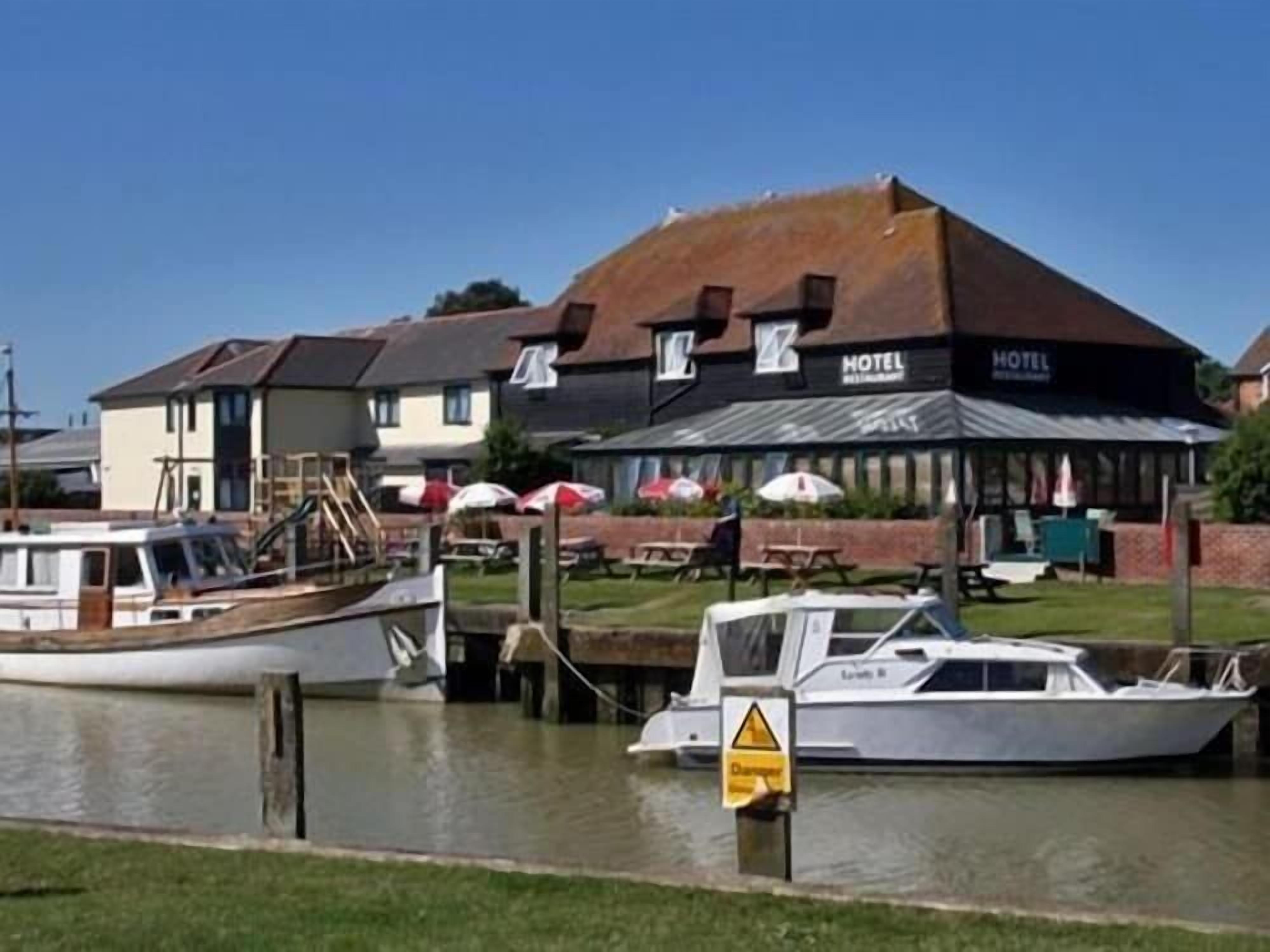 A hotel with a docked boat, a grassy area, and a sign indicating a caution area.