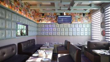A restaurant interior with booths, tables, and a wall-mounted TV.