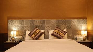 A hotel room with a large bed, two bedside lamps, and patterned wall tiles.