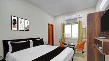 Habitación de hotel con cama, escritorio, dos sillas, armario y una obra de arte en la pared.