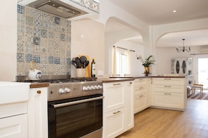 A modern kitchen with white cabinetry, a gas stove, and a patterned backsplash. - Casa Piscaretta with heated pool and close to sandy beaches (Porches)