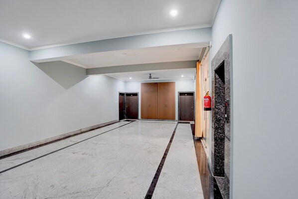 A spacious hallway with a marble floor, a ceiling with recessed lighting, and a fire extinguisher mounted on the wall. - Collection O IIT BHU Susu Wahi Varanasi (Varanasi)