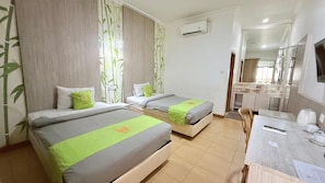 A hotel room with two beds, a desk, a chair, and a bathroom visible through an open door. - Hotel Huswah (Tangerang)