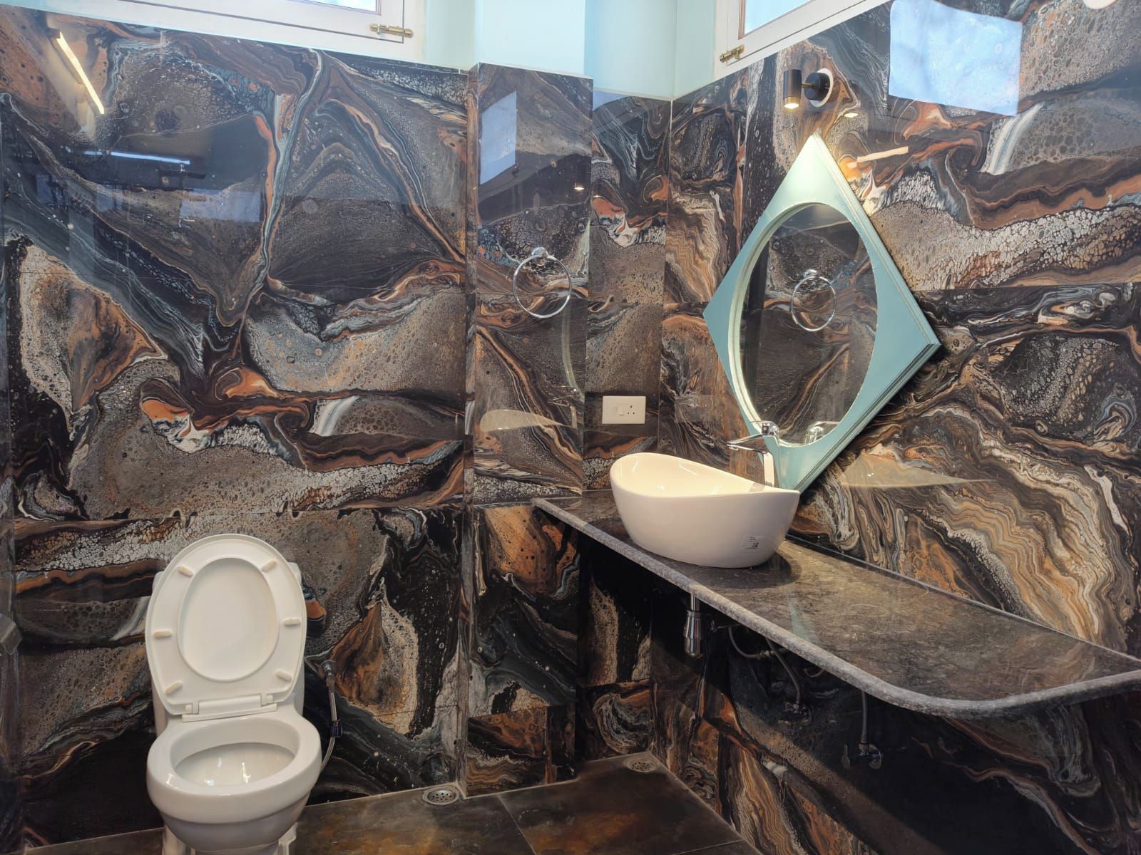 Un baño con tocador de mármol, un lavabo blanco y un espejo.