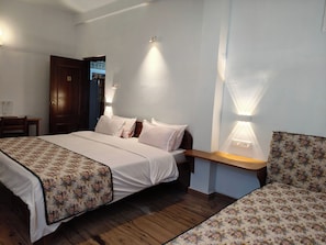 A hotel room with a bed, bedside tables, and a nightstand. - Tiggi's iing Heritage Homestay (Shillong)