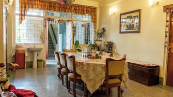 Un comedor con una mesa dispuesta para cuatro personas, rodeada de sillas, un fregadero y una escalera que lleva a un nivel superior.