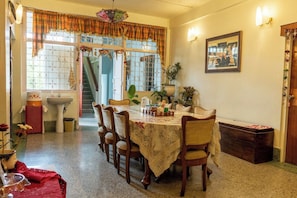 A dining area with a table set for four, surrounded by chairs, a sink, and a staircase leading to an upper level. - Tiggi's iing Heritage Homestay (Shillong)