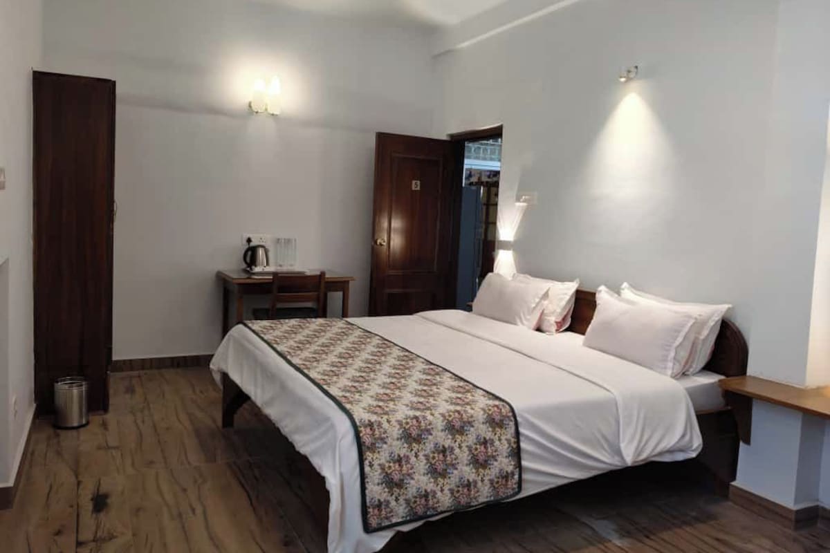 Un dormitorio con cama, mesita de noche y velador.