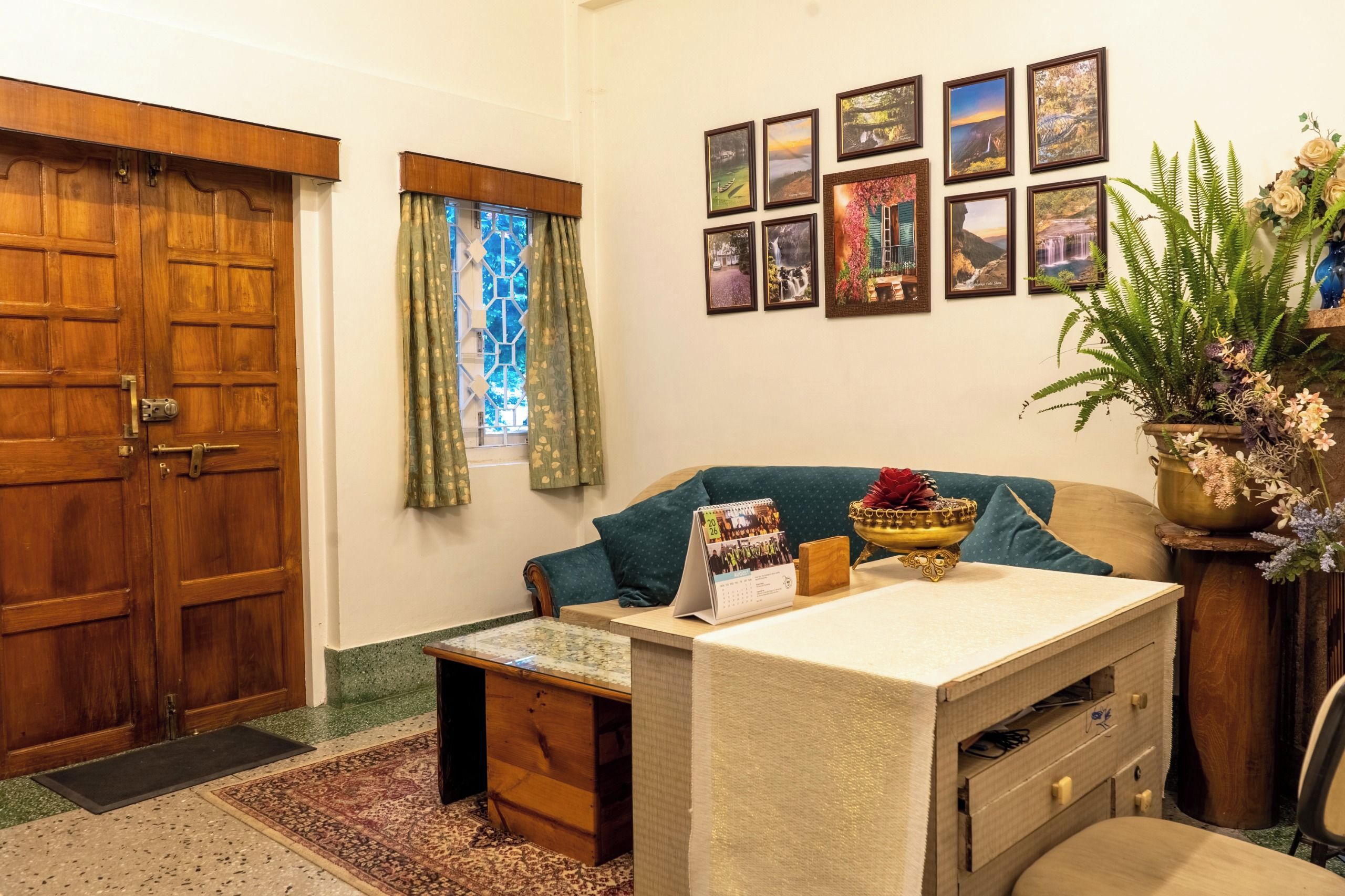 Une pièce chaleureuse avec une porte en bois, un petit bureau avec un calendrier, un canapé et un mur décoré de tableaux encadrés.