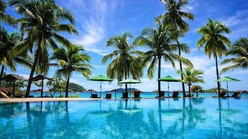 A poolside area with palm trees and lounge chairs.