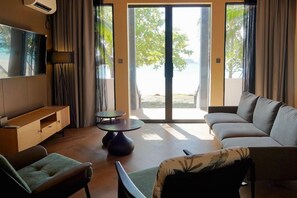 Una sala de estar moderna con un sofá, una silla, una mesita y un televisor montado en la pared.