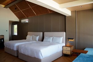 Un dormitorio con dos camas, techo de madera y una mesita de noche con lámpara.