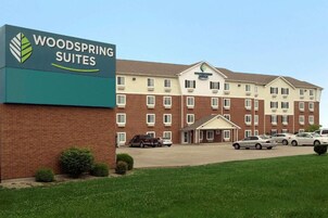 A hotel with a sign reading 'WOODSPRING SUITES' and a brick facade.