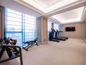 Un gimnasio con cintas de correr, mancuernas y una banca.