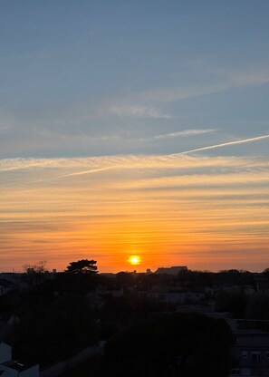 A sunset over a residential area with a clear sky and a visible contrail. - A beautiful apartment located just 600 meters from downtown La Rochelle (La Rochelle)