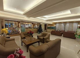 Un vestíbulo de hotel con zonas de estar, un mostrador de recepción y un árbol de Navidad.