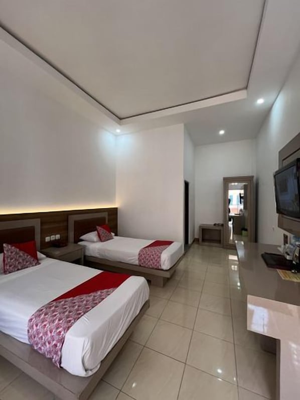 Habitació d'hotel amb dos llits, un televisor i escriptori.