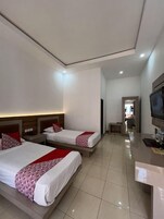 Habitación de hotel con dos camas, un televisor y un escritorio.